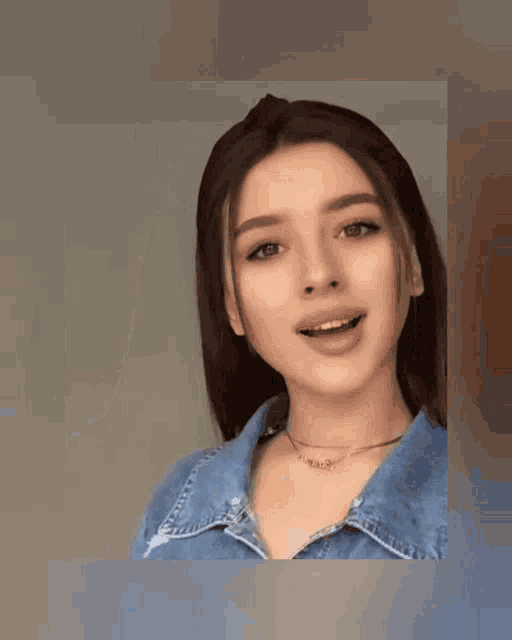 a woman wearing a choker and a denim shirt is smiling for the camera
