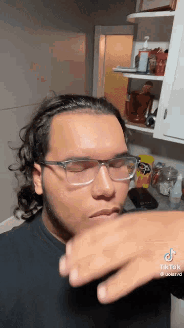 a man wearing glasses is standing in front of a shelf with a bag of pringles on it .