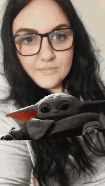 a woman wearing glasses holds a stuffed animal in front of her face