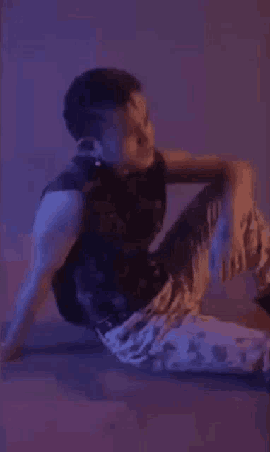 a man is sitting on the floor with his legs crossed in a dark room .