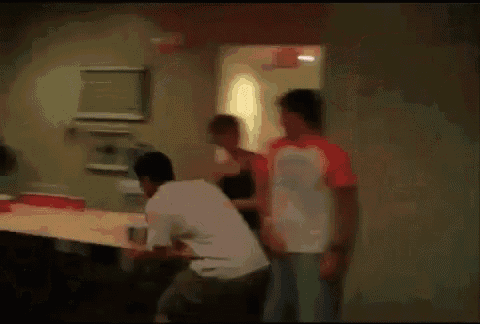 a group of people dancing in a room with a red exit sign on the wall