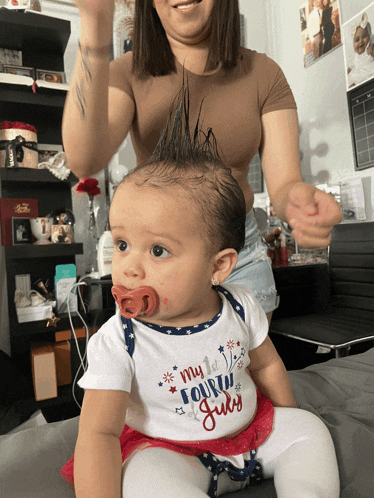 a baby with a pacifier in her mouth wears a shirt that says my fourth of july