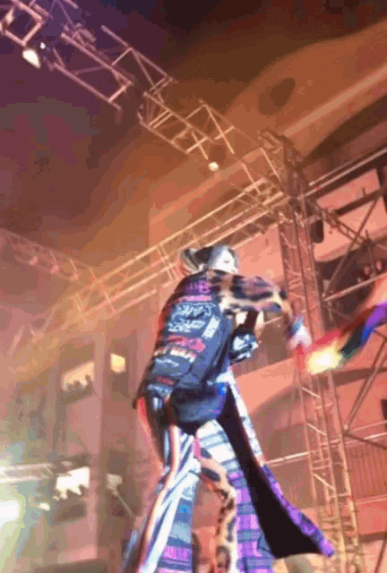 a man in a blue and purple costume is dancing on stilts