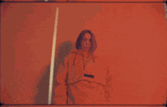 a person in an orange hoodie is standing in front of a cross
