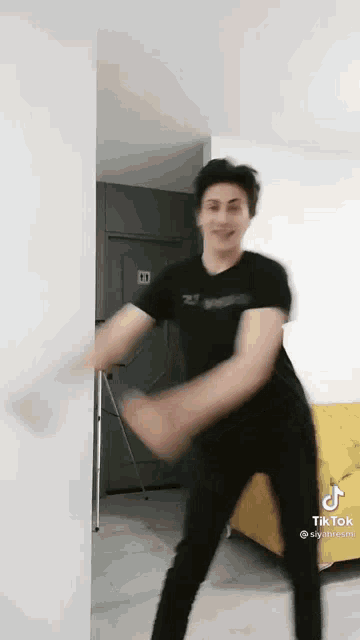 a man in a black shirt and black pants is dancing in a room .