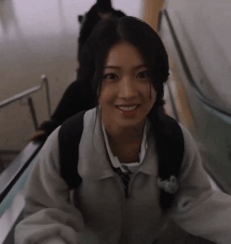 a girl is smiling while riding an escalator with a backpack on her back