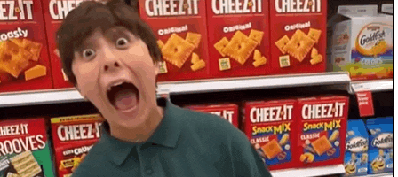 a young boy is standing in front of a shelf of cheez-it snack mix