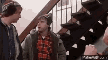 three men are standing next to each other on a set of stairs talking to each other .