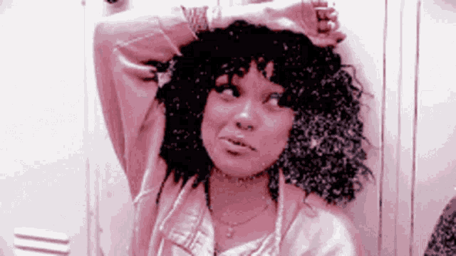 a woman with curly hair is standing in front of a white locker