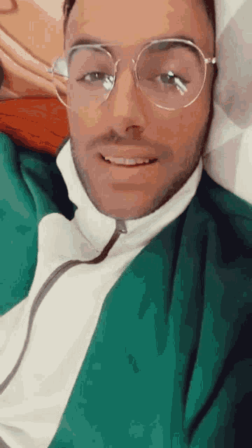 a man wearing glasses and a green jacket smiles