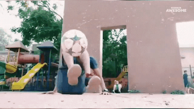 a man is doing a trick with a soccer ball at a playground .