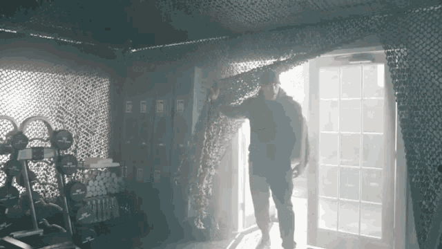 a man standing in a room with a camouflage net on the wall