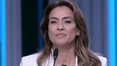 a woman in a white jacket is standing in front of a microphone and smiling .