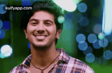 a young man in a plaid shirt is smiling .