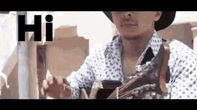 a man in a cowboy hat is playing a guitar in a video .