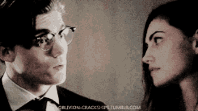 a man in a suit and tie is looking at a woman with glasses ..