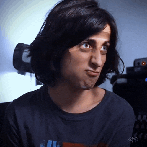 a man with long hair is wearing a black shirt with the letters agii on the front