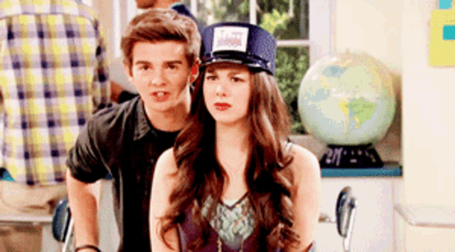 a boy and a girl are standing next to each other and the girl is wearing a hat that says i love you