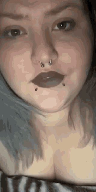 a close up of a woman with a nose ring and black lipstick