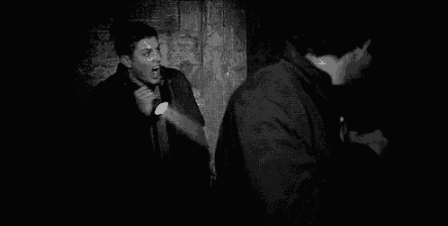 a man is holding a flashlight in a dark room and shouting .