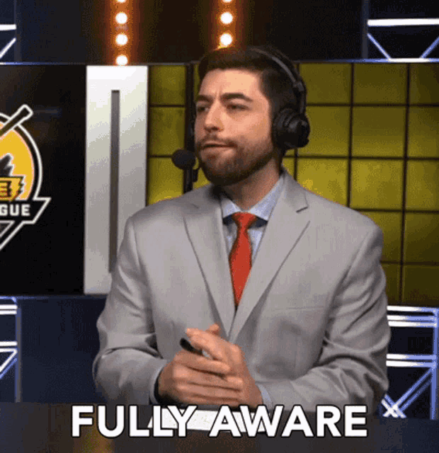 a man in a suit and tie says fully aware while wearing a headset
