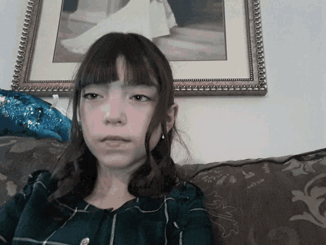 a young girl sits on a couch in front of a framed picture of a bride and groom
