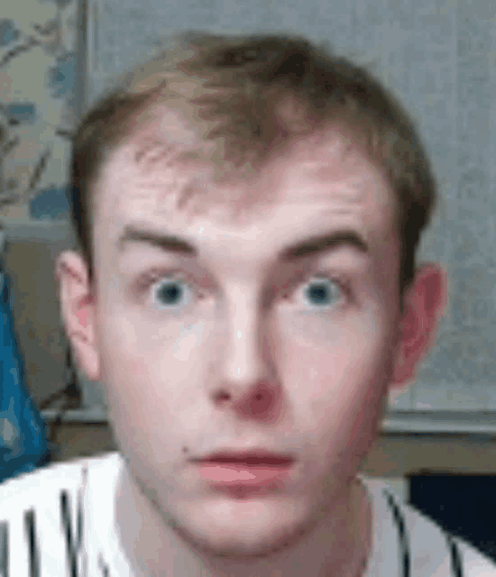 a young man with blonde hair and blue eyes is looking at the camera .
