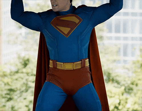 a man in a superman costume stands with his arms up