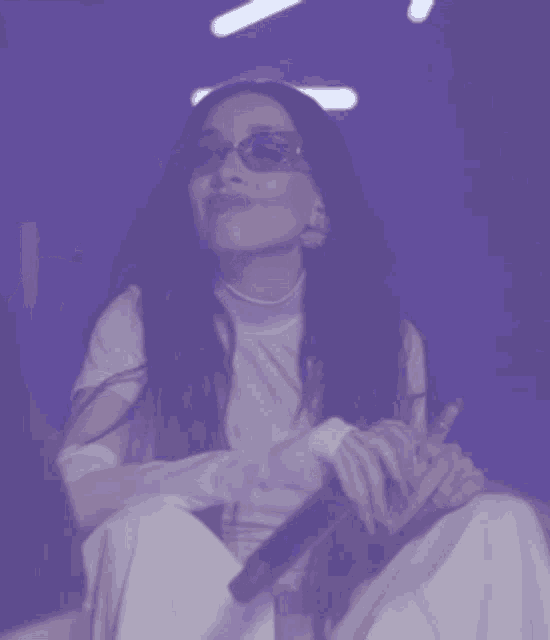 a woman wearing sunglasses is singing into a microphone on a stage .