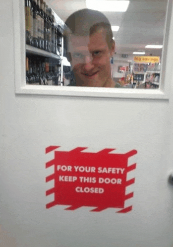 a man behind a glass door with a for your safety keep this door closed sign