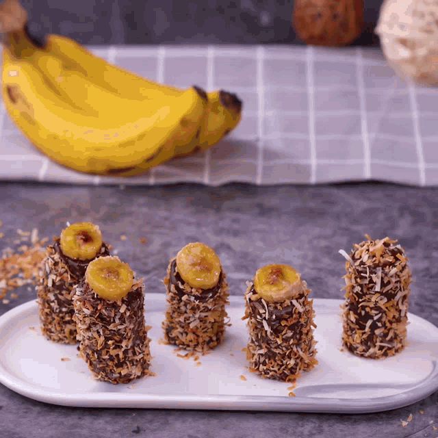 a bunch of bananas covered in chocolate and coconut are on a white plate