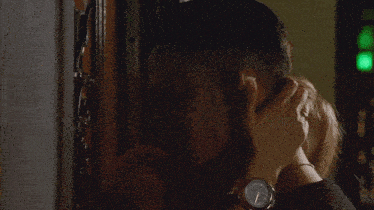 a woman holds a man 's head while a green light is behind them