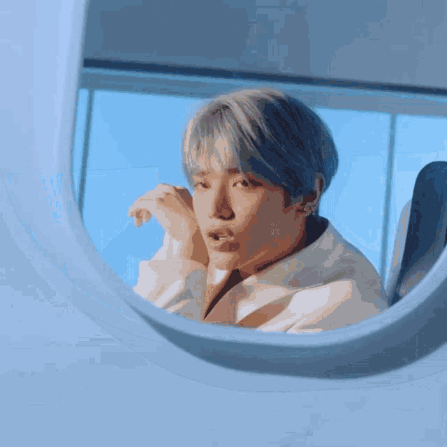 a man with blue hair is looking at himself in the mirror .