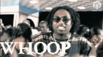 a man wearing sunglasses is standing in front of a crowd of people .