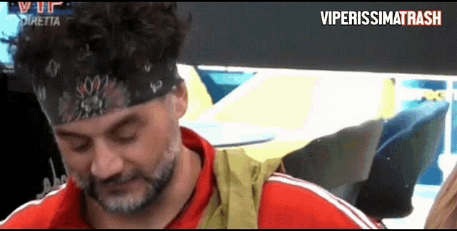 a man with a beard wearing a headband and a red shirt with the words viperissimo trash written on the bottom
