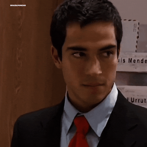 a man in a suit and tie stands in front of a wall with endez g on it