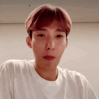 a man with pink hair is wearing a white shirt and making a funny face .