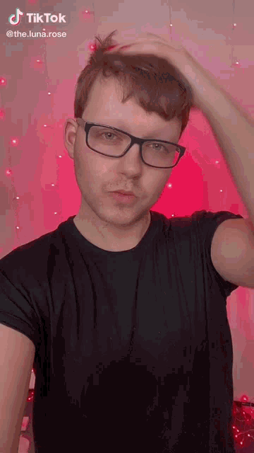 a man wearing glasses and a black shirt is making a funny face