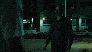 a man wearing a white t-shirt with a skull on it looks at the camera
