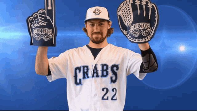 a man wearing a blue crabs jersey holds up foam hands