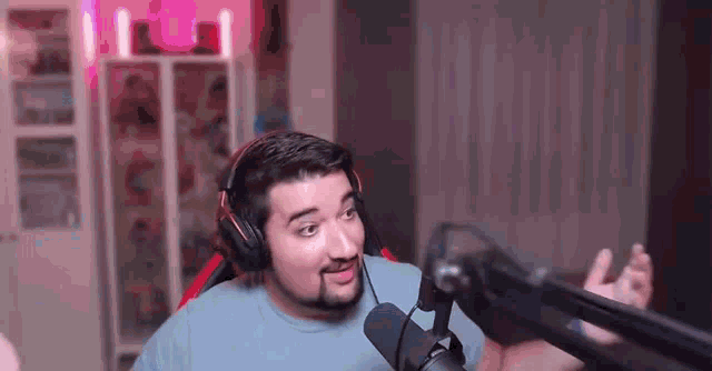a man with a beard is wearing headphones and standing in front of a microphone in a room .