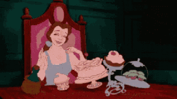 belle from beauty and the beast is sitting at a table with a cake on it