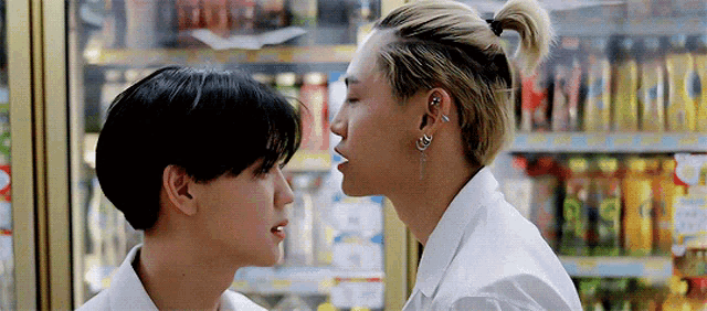 two men are kissing each other in front of a refrigerator .