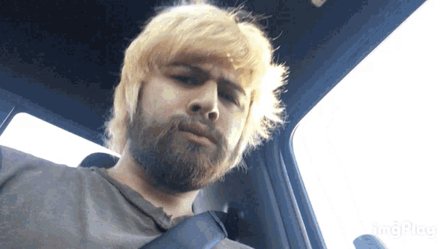 a man with blonde hair and a beard is sitting in the back seat of a car