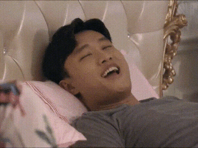 a man is laying on a bed with his eyes closed and his mouth open