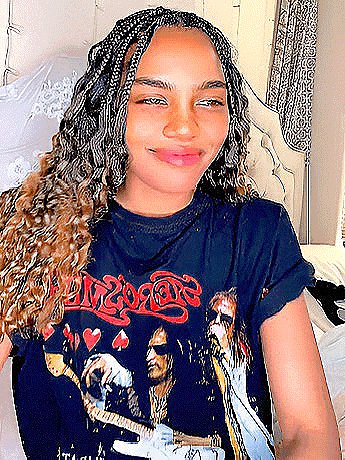 a young woman with braids is wearing a black t-shirt with a picture of a man playing a guitar .