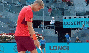 a man in a red shirt is holding a tennis racquet on a longi court