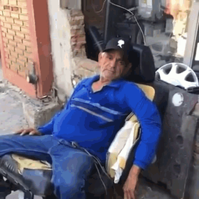 a man in a blue shirt and hat is sitting on a chair
