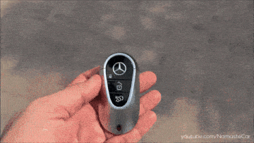 a hand is holding a mercedes key fob