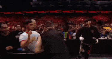 a man is hugging another man in a wrestling ring in front of a crowd .